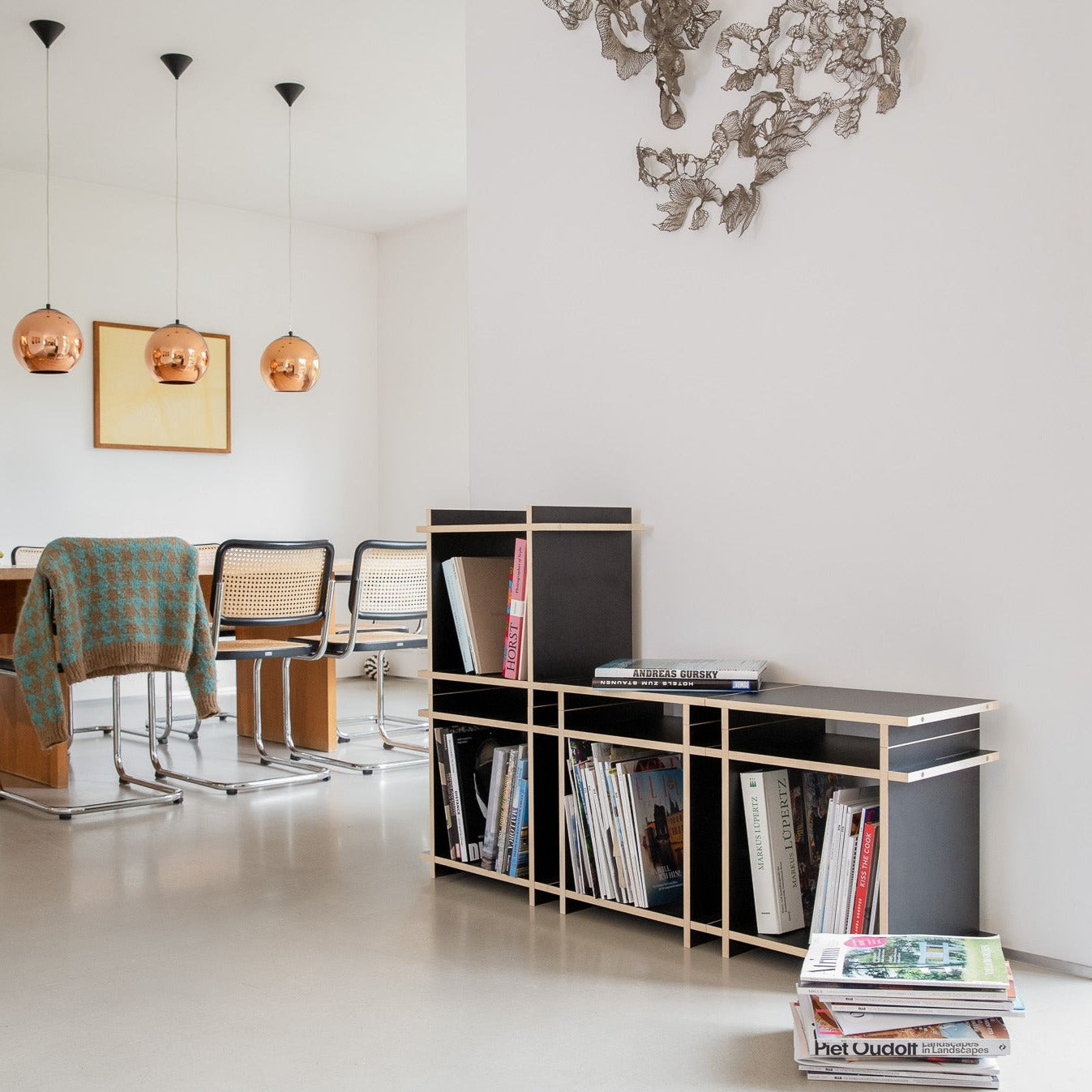 Regal mit Büchern bestehend aus schwarzen Würfeln in einem moderenen Raum.