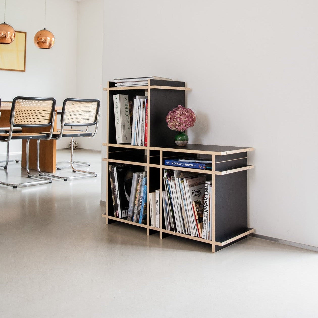 Regal mit Büchern bestehend aus schwarzen Würfeln in einem moderenen Raum.