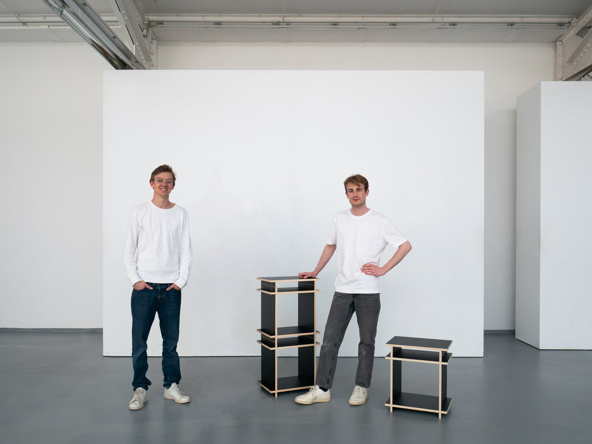 Die beiden Gründer von Kiyo im Studio neben einem schwarzen Regalwürfel des modularen Systems.