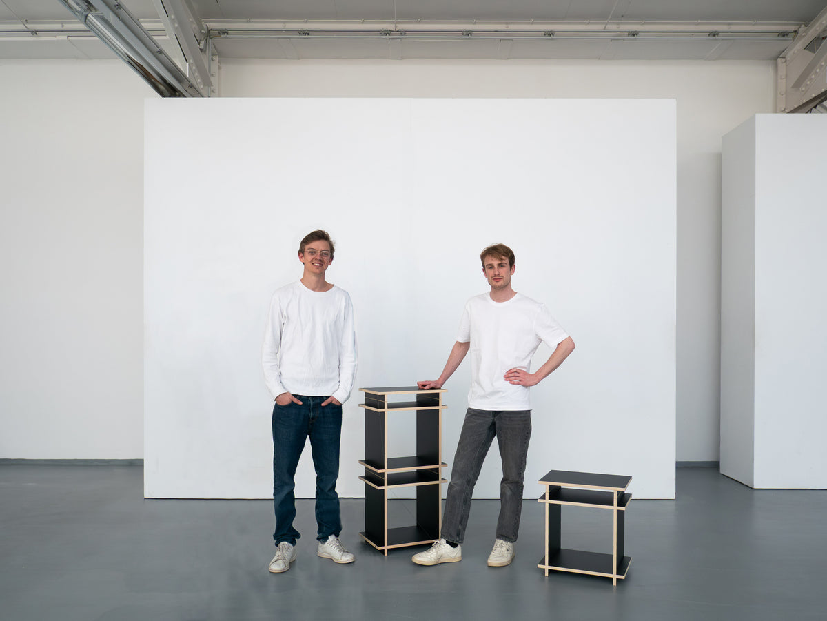 Die beiden Gründer von Kiyo im Studio neben einem schwarzen Regalwürfel des modularen Systems.