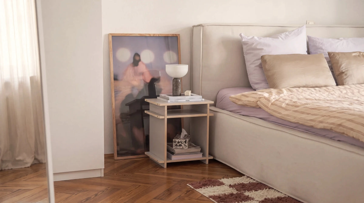 Nachttisch von Kiyo in Cashmere aus einem Cube und einem Cap neben dem Bett, mit Leuchte und Magazinen.