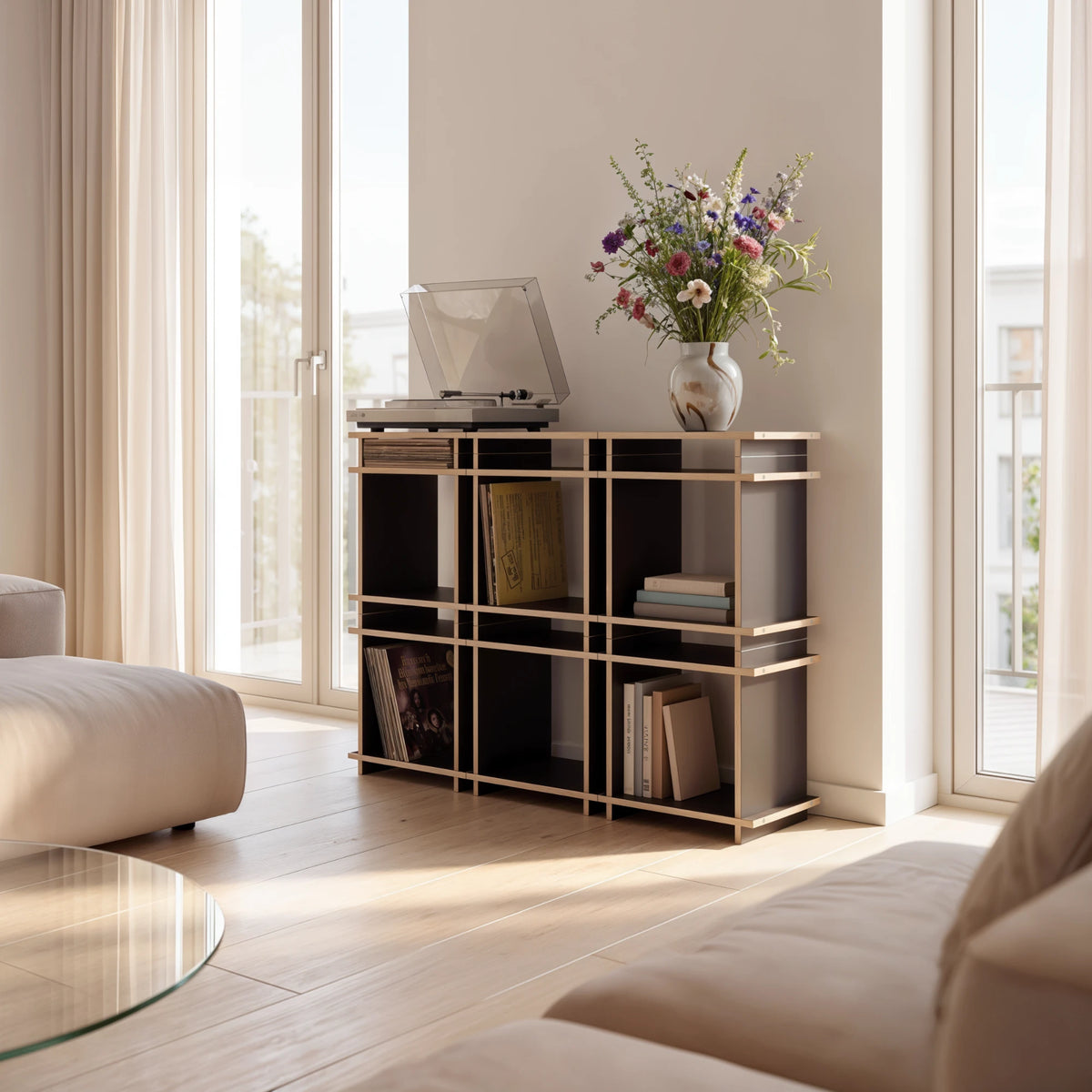 R1 Highboard Bundle in Schwarz von Kiyo als Regal im Wohnzimmer, mit Plattenspieler, Schallplatten und Blumenstrauß.