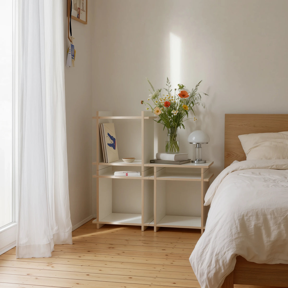 R1 Triangle Bundle in Weiß von Kiyo als Regal neben dem Bett, mit Blumen, Leuchte und Büchern.