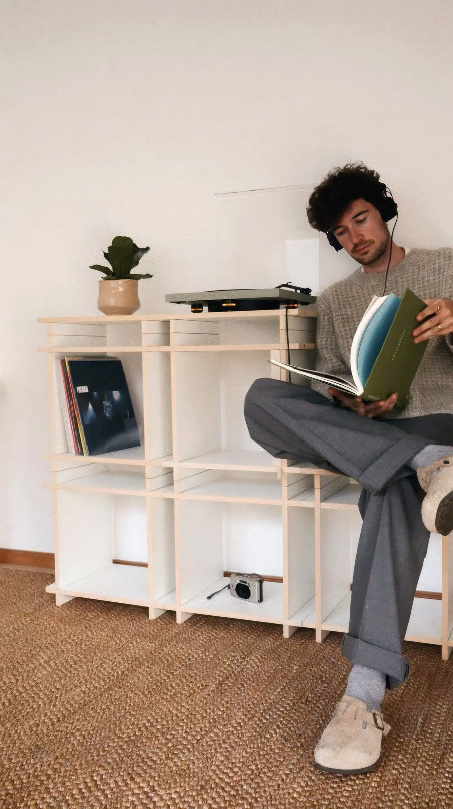 person sitzt auf einem Regal und ört Musik von Schallplatten.
